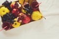 Red fresh juice with apples, pears, bananas, grapes and pomegranate fruits in white wooden tray on bed sheet. Royalty Free Stock Photo