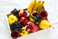 Red fresh juice with apples, pears, bananas, grapes and pomegranate fruits in white wooden tray on bed sheet. Top view. Healthy l Royalty Free Stock Photo