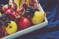 Red fresh juice with apples, pears, bananas, grapes and pomegranate fruits in white wooden tray on blue bed shee Royalty Free Stock Photo