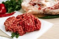 Red fresh minced meat on the background of lamb legs, red pepper and greens. Ground beef on the background of fresh meat in the Royalty Free Stock Photo