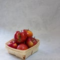 Red fresh organic apples in small wooden pottle with ugly fruit on top. On grey cement background with copy space