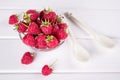 Red fresh raspberries in a glass bowl with green leaves on white background. Top view Royalty Free Stock Photo