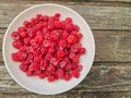 Red fresh raspberries on rustic wood background. Bowl with natural ripe organic berries with peduncles on wooden table Royalty Free Stock Photo