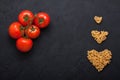 Red fresh tomatoes and pasta heart shape black concrete background. Royalty Free Stock Photo