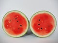 Red fresh watermelon fruit, cut in half into circles, facing out into 2 pieces, the juicy red flesh and black seeds inside on whit Royalty Free Stock Photo