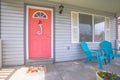 Red front door of house with blue porch chairs against windows with shutters Royalty Free Stock Photo