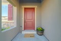 The red front door of a house with concrete exterior wall and shutters on window Royalty Free Stock Photo