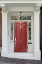 Red Front Door with White Door Frame and Windows on Brick Street Royalty Free Stock Photo
