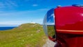 Red front light of old motorbike from Czech Republic in England with blurred lighthouse in background Royalty Free Stock Photo