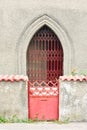 Red front metal gate and the arch of an old building