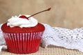 Red fruit cake cupcake with whipped cream and a cherry on top punch the table on blurred background with space for text Royalty Free Stock Photo