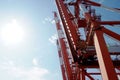 Red gantry cranes with white stripes in vertical position in container terminal with blue sky in background waiting for loading. Royalty Free Stock Photo