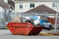 Red garbage removal skip full of rubbish and ready for collection in a street. Old dumpster full of junk in a yard. Waste industry Royalty Free Stock Photo