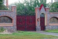 Red gate and a door made of metal with a forged pattern and a stone fence in the street Royalty Free Stock Photo