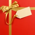 Red gift background, gold ribbon bow, blank gift tag or label, copy space, vertical Royalty Free Stock Photo