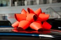 a red gift bow on the roof of a new black car in the car dealership. Royalty Free Stock Photo