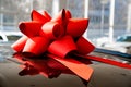 a red gift bow on the roof of a new black car in the car dealership. Royalty Free Stock Photo