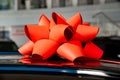 a red gift bow on the roof of a new black car in the car dealership. Royalty Free Stock Photo