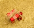 Red gift box and baubles with gold ribbon on a gold glitter back Royalty Free Stock Photo