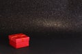 Red gift box on black sparkling glittery background. Photo with selective focus. Backdrop with copy space Royalty Free Stock Photo