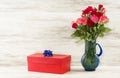 Red gift box with a blue bow and roses on a background of vintage boards Royalty Free Stock Photo