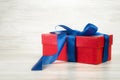 Red gift box with a blue ribbon on a background of vintage boards Royalty Free Stock Photo