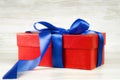 Red gift box with a blue ribbon on a background of vintage boards Royalty Free Stock Photo