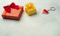 Red gift box with a bow next to a yellow box and a keychain in the shape of a heart on a light blue background on Valentine`s day Royalty Free Stock Photo