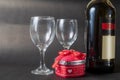 Red gift box with red bow and wine bottle with two wine glasses on black background. Valentine\'s day Royalty Free Stock Photo