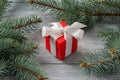 Red gift box with a bow on a wooden surface among the fir branches Royalty Free Stock Photo