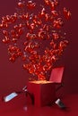 Red gift box with crimson bow opens with an explosion of heart-shaped balloons.