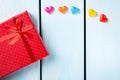 Red gift box with decorative hearts on nice blue wooden background Royalty Free Stock Photo
