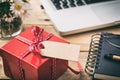 Red gift box with empty blank tag, blur office desk background Royalty Free Stock Photo