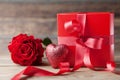 Red gift box, glitter heart and rose flower on wooden background. Mother or Valentines day greeting card. Royalty Free Stock Photo