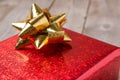 Red gift box gold bow on wood table, close up Royalty Free Stock Photo