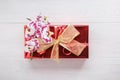 Red gift box with golden ribbon bow and orchid flower on white wooden table. Top view. Flat lay. Copy space Royalty Free Stock Photo