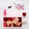 Red gift box with golden ribbon bow and orchid flower on white wooden table. Top view. Flat lay. Copy space Royalty Free Stock Photo