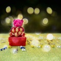 A red gift box with golden ribbon for celebrate Christmas and happy new year with a pink Teddy bear that standing on green fabric Royalty Free Stock Photo