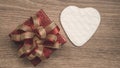 Red gift box with golden ribbon and white heart paper cut for surprise valentines day present on brown wooden background, top view Royalty Free Stock Photo