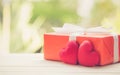 Red gift box and heart shape on wood table top with nature green blur bokeh background Royalty Free Stock Photo