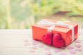 Red gift box and heart shape on wood table top with nature green blur bokeh background. Royalty Free Stock Photo