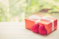 Red gift box and heart shape on wood table top with nature green blur bokeh background Royalty Free Stock Photo