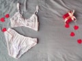 Red gift box, hearts and women`s pink lingerie lying at grey bed as backdrop