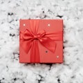 A red gift box in the middle of white fake fiberfill snow. Top view. Square format Royalty Free Stock Photo