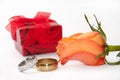 Red gift box with pair of engagement rings and orange rose Royalty Free Stock Photo