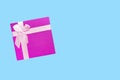 Red gift box with pink ribbon isolated on blue background. Royalty Free Stock Photo