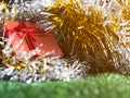 Red gift box with red ribbon bow and golden seam place on silver and gold rainbow glowing decoration background on green grass. Royalty Free Stock Photo