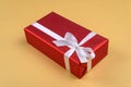 Red gift box with ribbon and bow on golden background, copy space. Holiday greeting card. Mothers day, birthday. Royalty Free Stock Photo