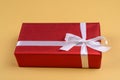 Red gift box with ribbon and bow on golden background, copy space. Holiday greeting card. Royalty Free Stock Photo