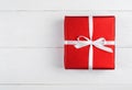 Red gift box with ribbon and bow on white wooden background, copy space. Holiday greeting card. Mothers day, birthday, Womens Day Royalty Free Stock Photo